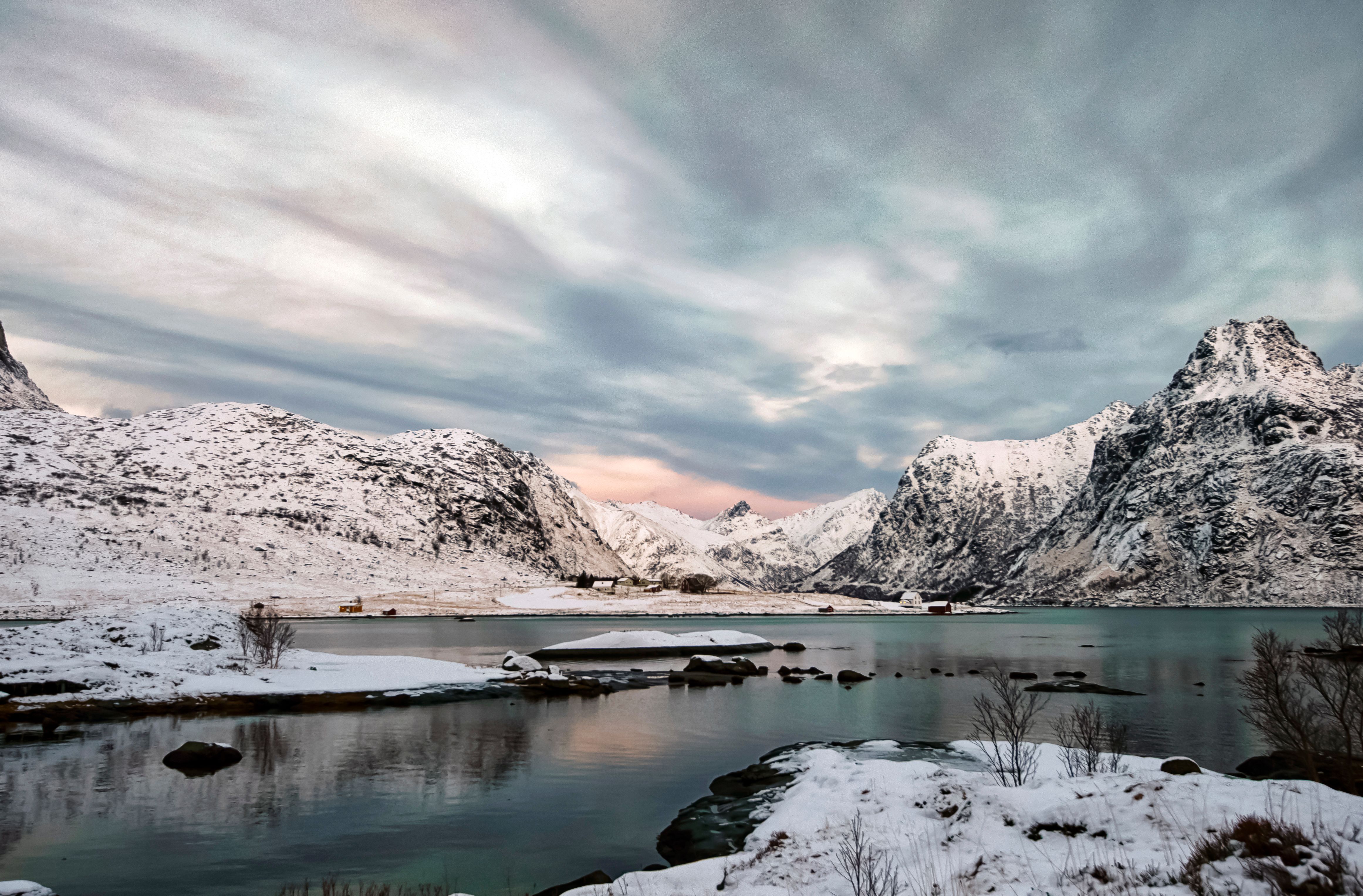 Snowy mountains rise over a fjord in Flakstad, Norway, showcasing a dramatic winter destination.