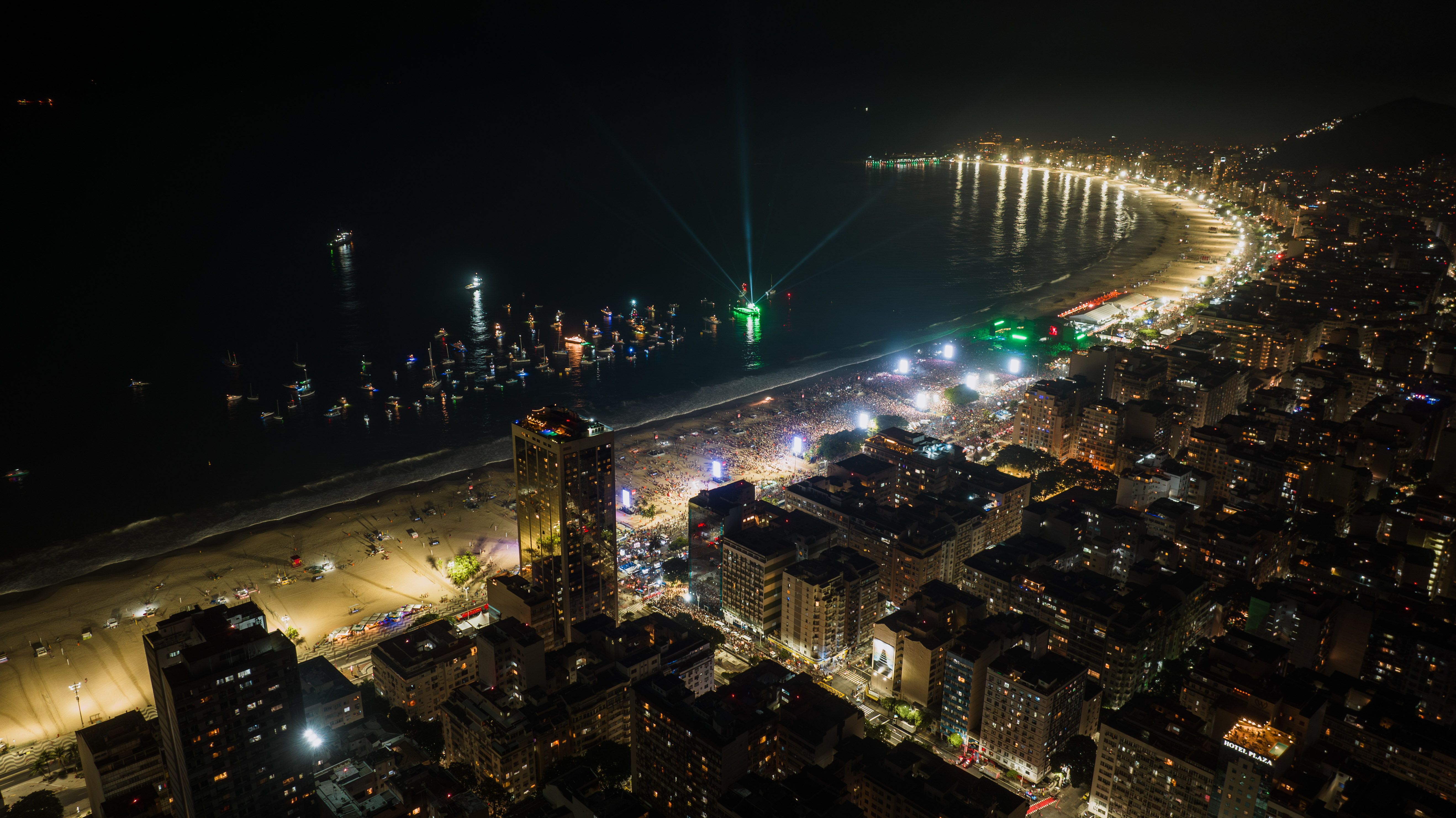 Aerial nighttime view of Copacabana Beach and Rio de Janeiro's brightly lit coastline.