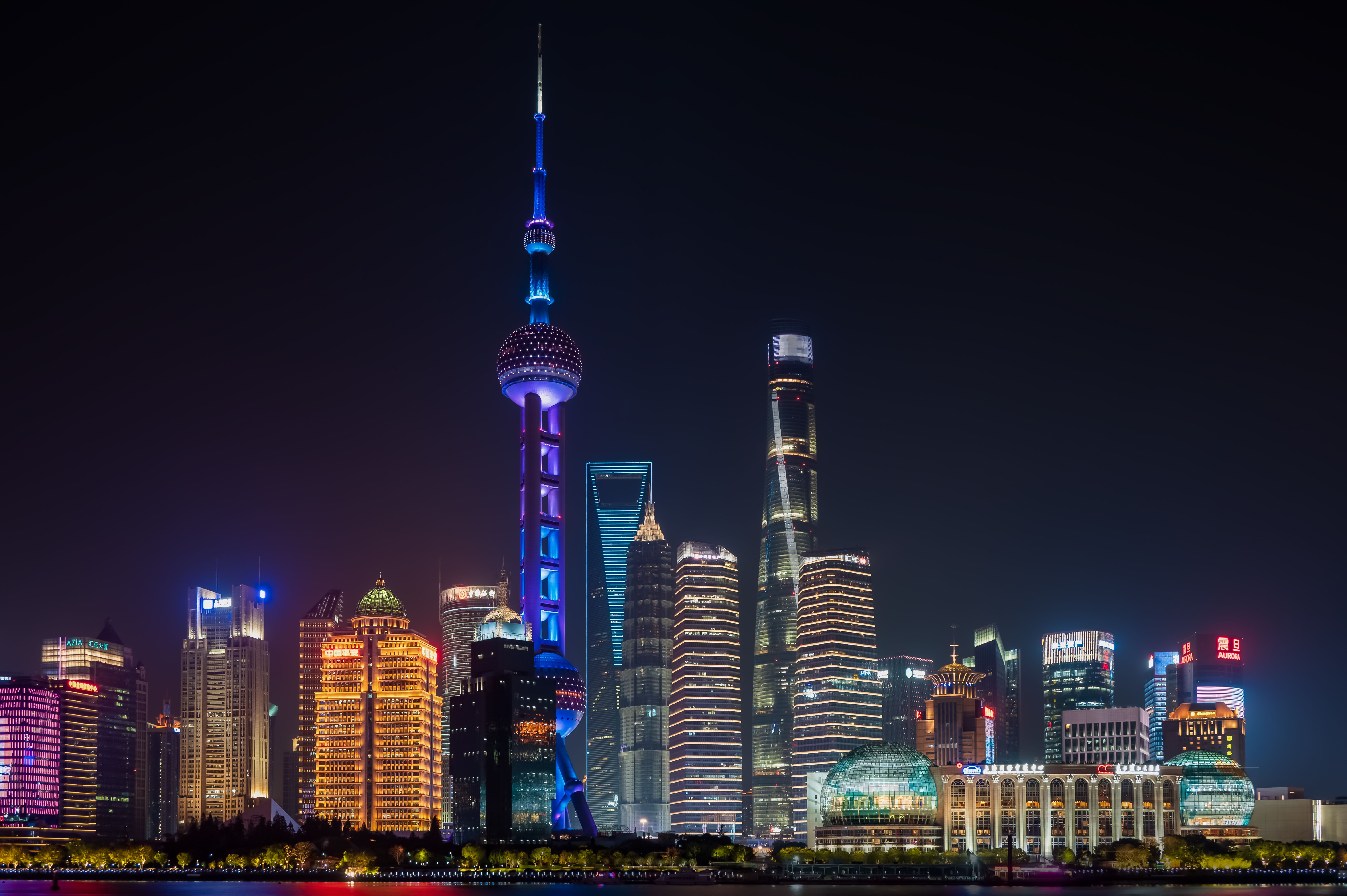 Shanghai's illuminated skyline and Oriental Pearl Tower shining against the night sky.