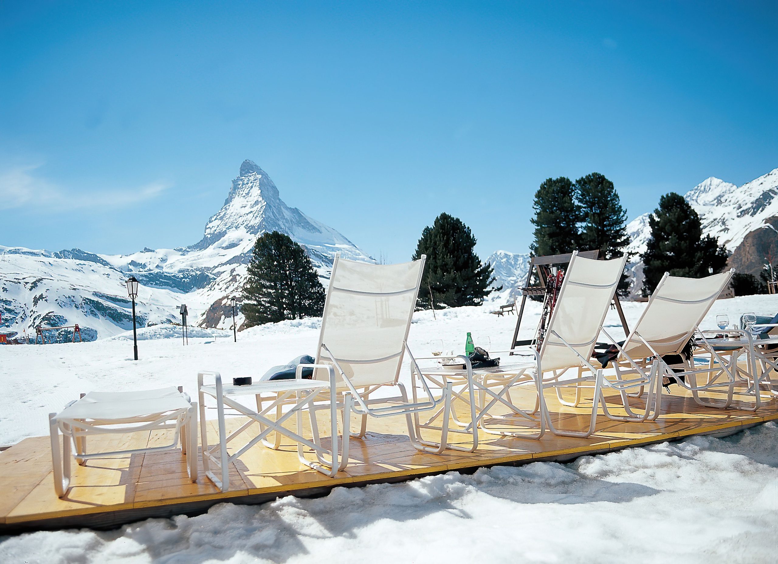Lounge chairs overlook the Matterhorn and snowy Swiss Alps, a classic winter mountain getaway.
